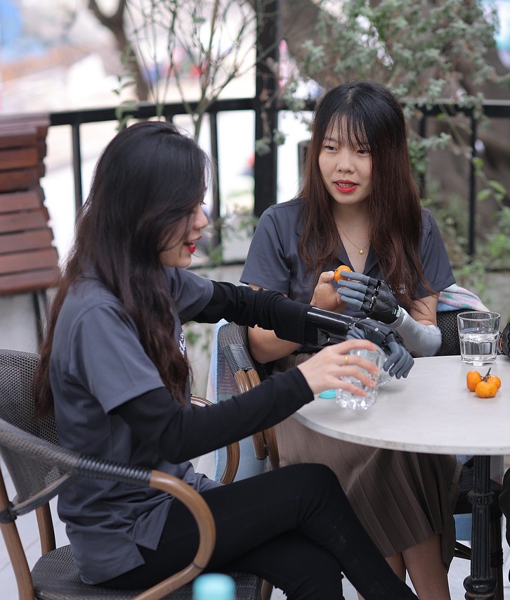     Two women with prosthetic hands having a drink